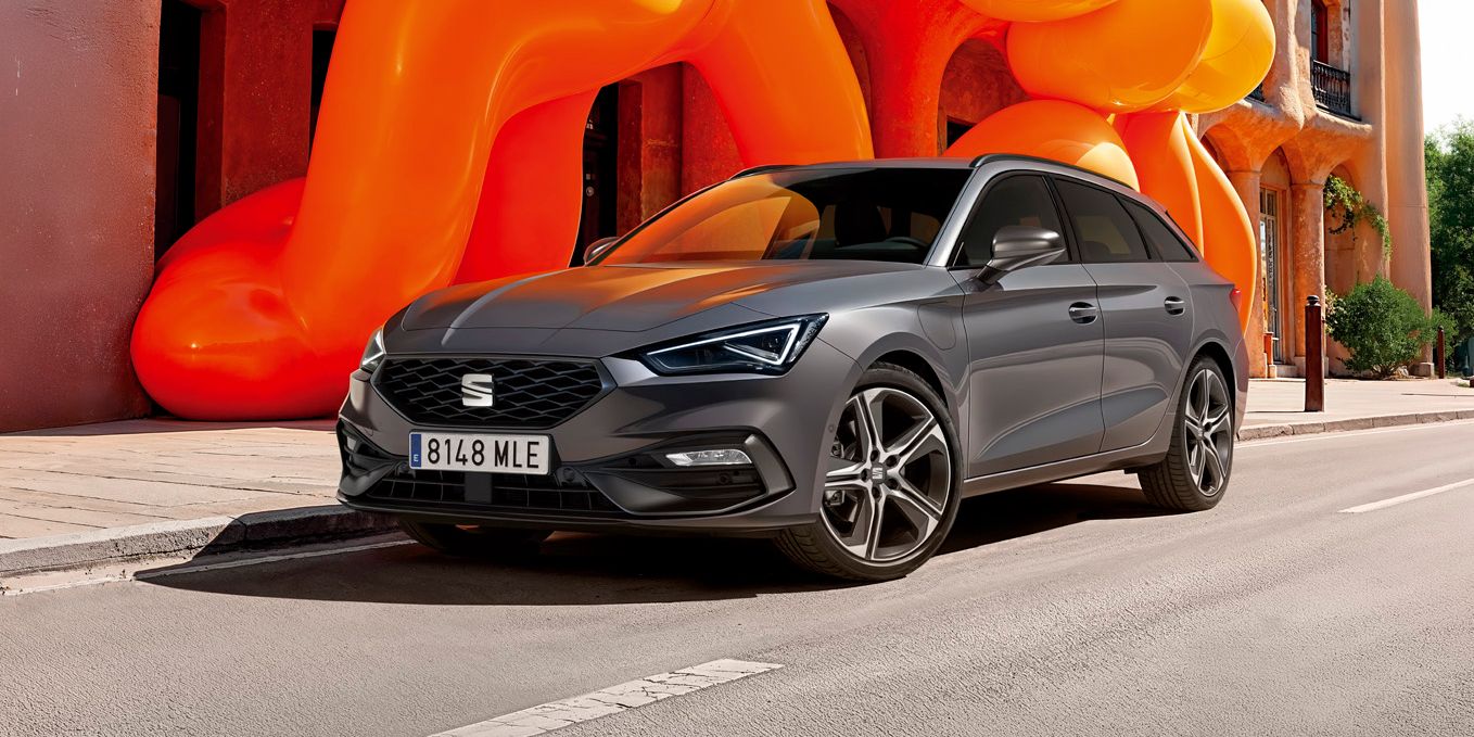 SEAT Leon stojí pred historickou budovou s modernou oranžovou inštaláciou. 