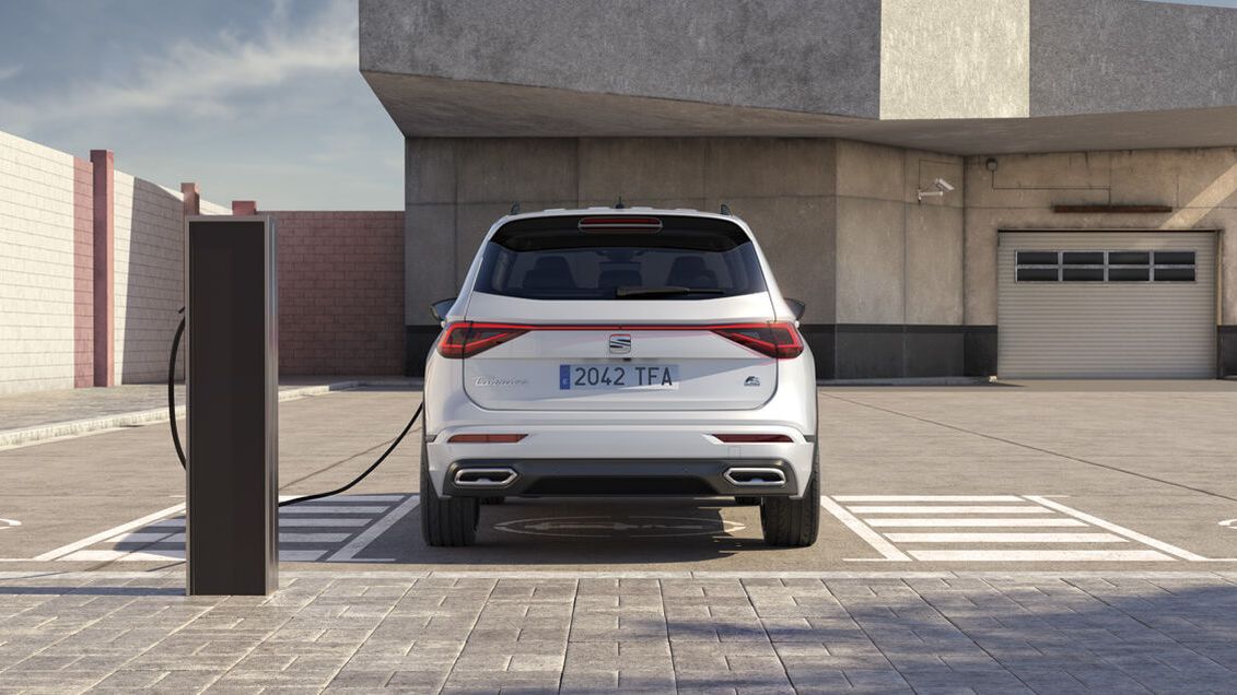 SEAT Tarraco zo zadného pohľadu stojí na parkovacom mieste pri verejnej nabíjacej stanici pred betónovou budovou.