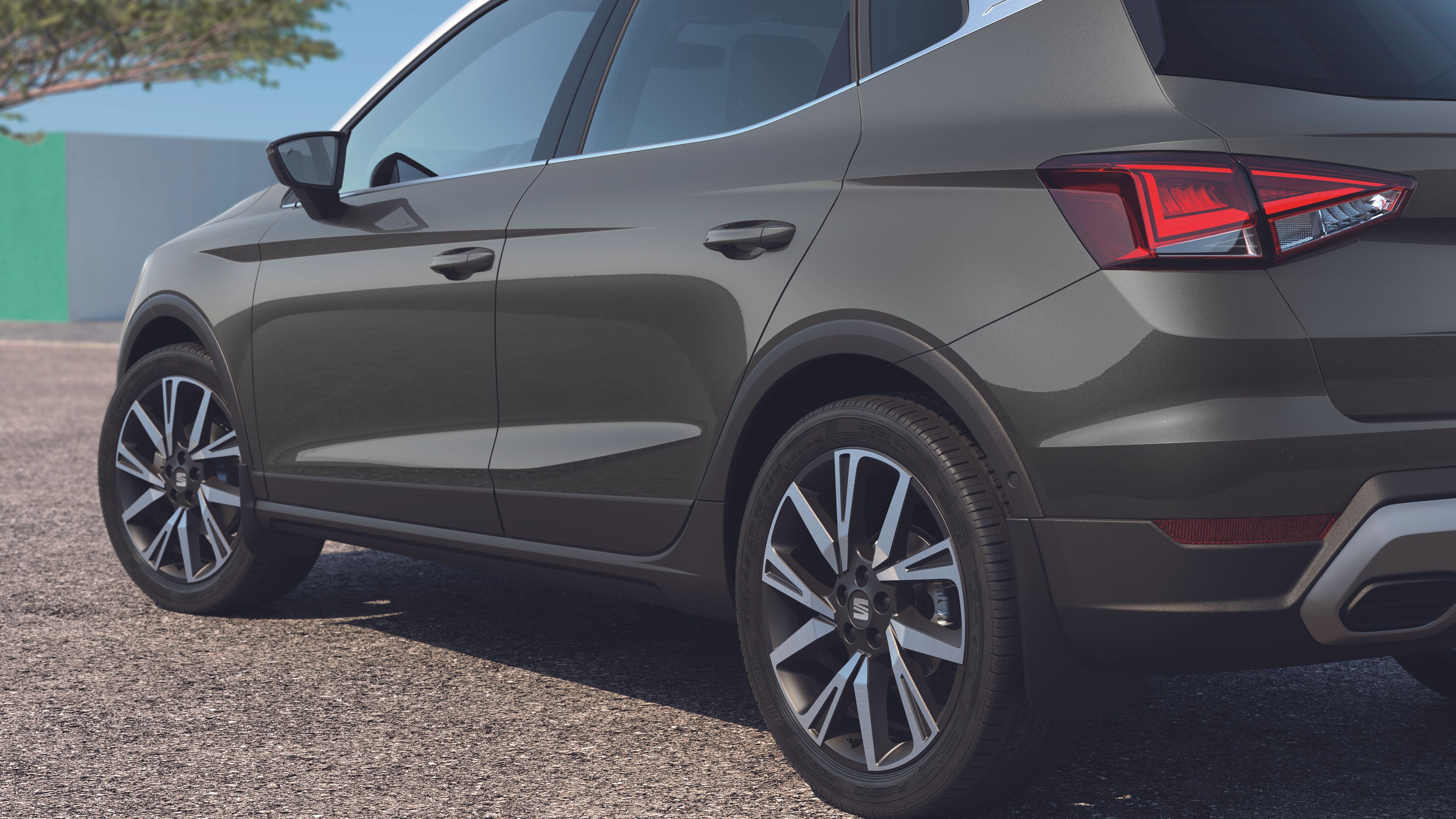 SEAT Arona zaparkovaná pri strome a bielo-zelenom múre.