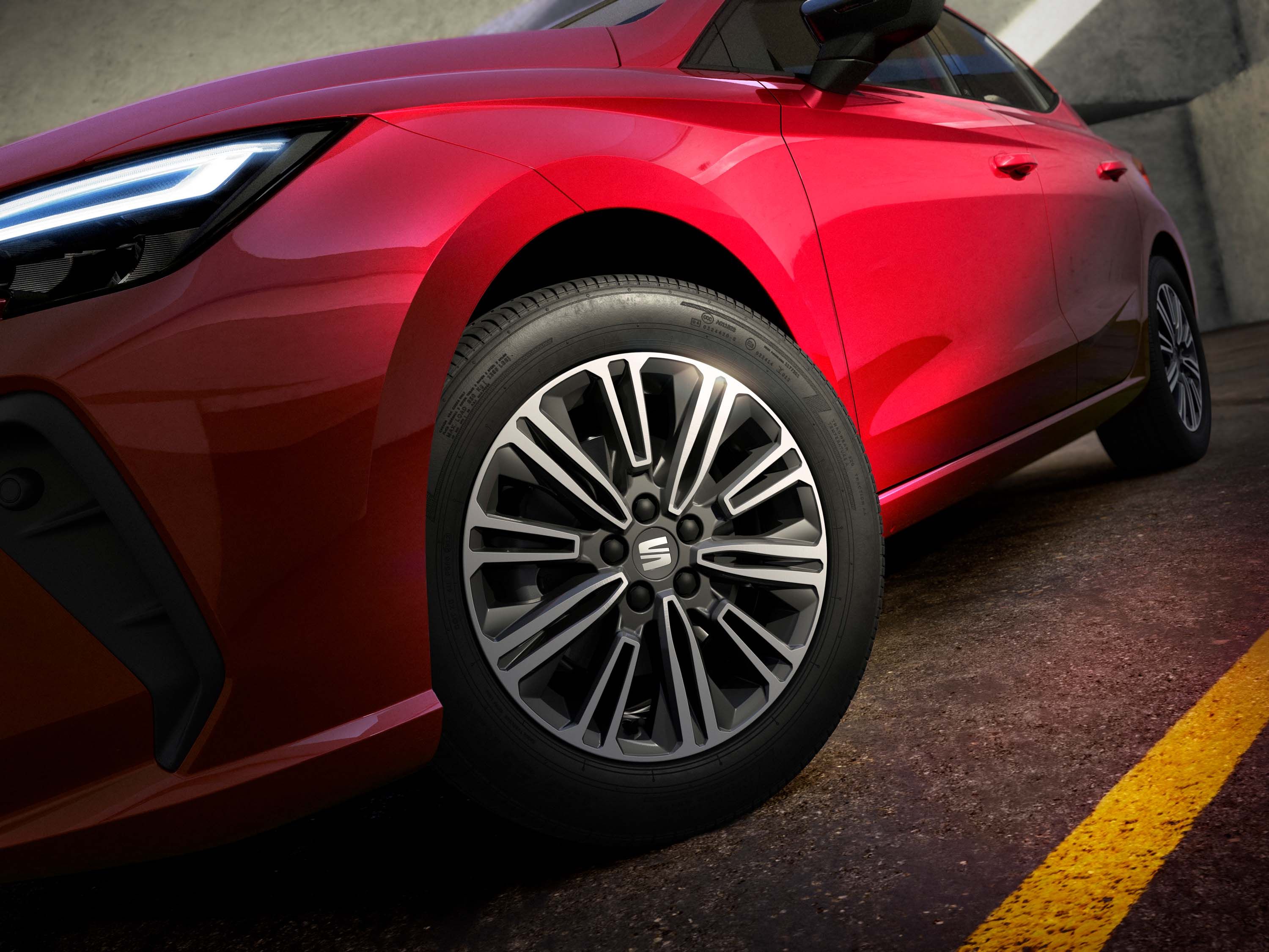 Červený automobil s výraznými LED svetlami a elegantnými kolesami stojí na asfaltovej ceste. Kolesá majú moderný dizajn s viacerými lúčmi. Scéna je osvetlená prirodzeným svetlom.