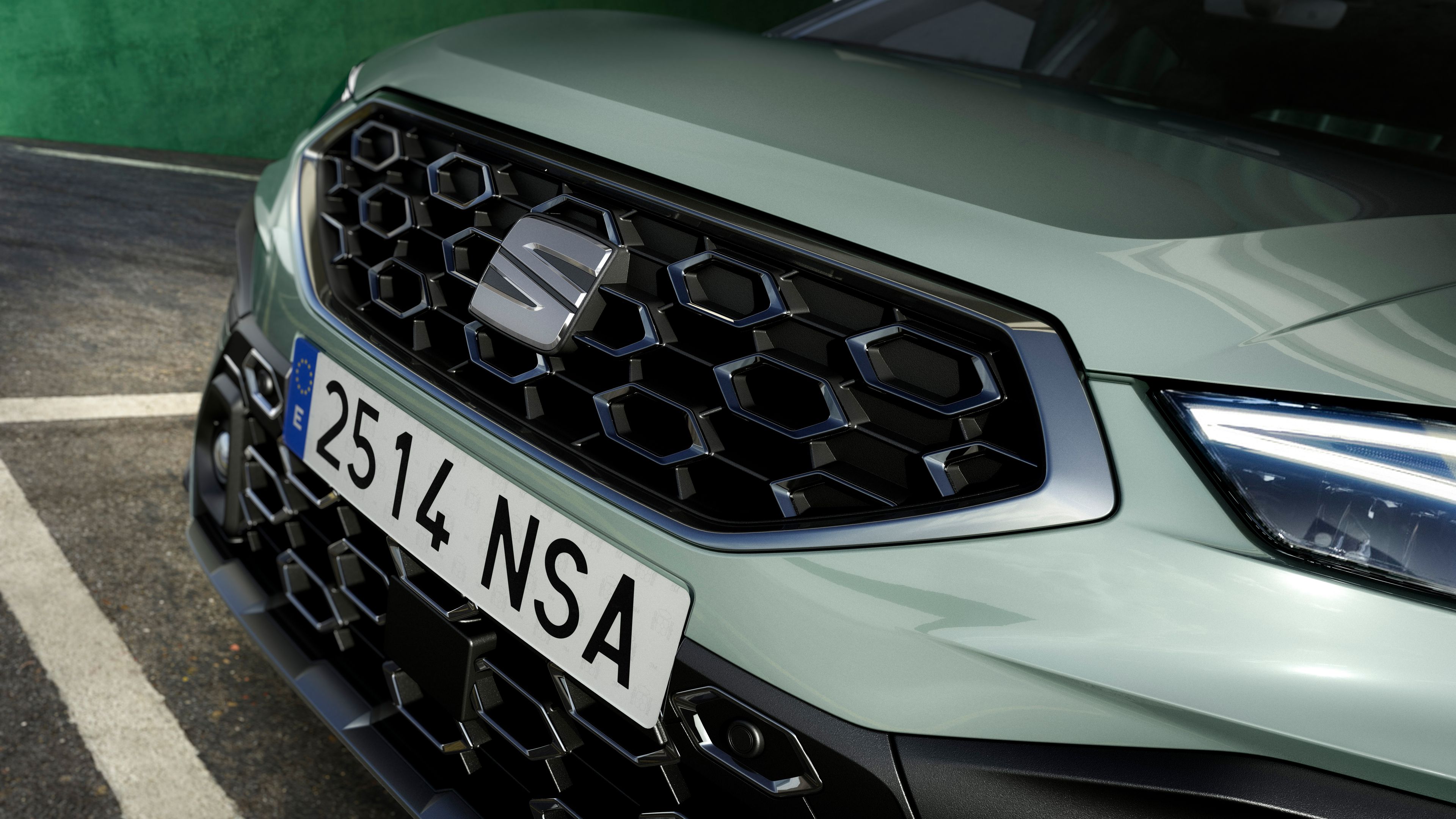 Automobil značky SEAT so zeleným lakom. Detailný pohľad na prednú masku s registračnou značkou. Masku zdobia elegantné čierne hexagonálne vzory.