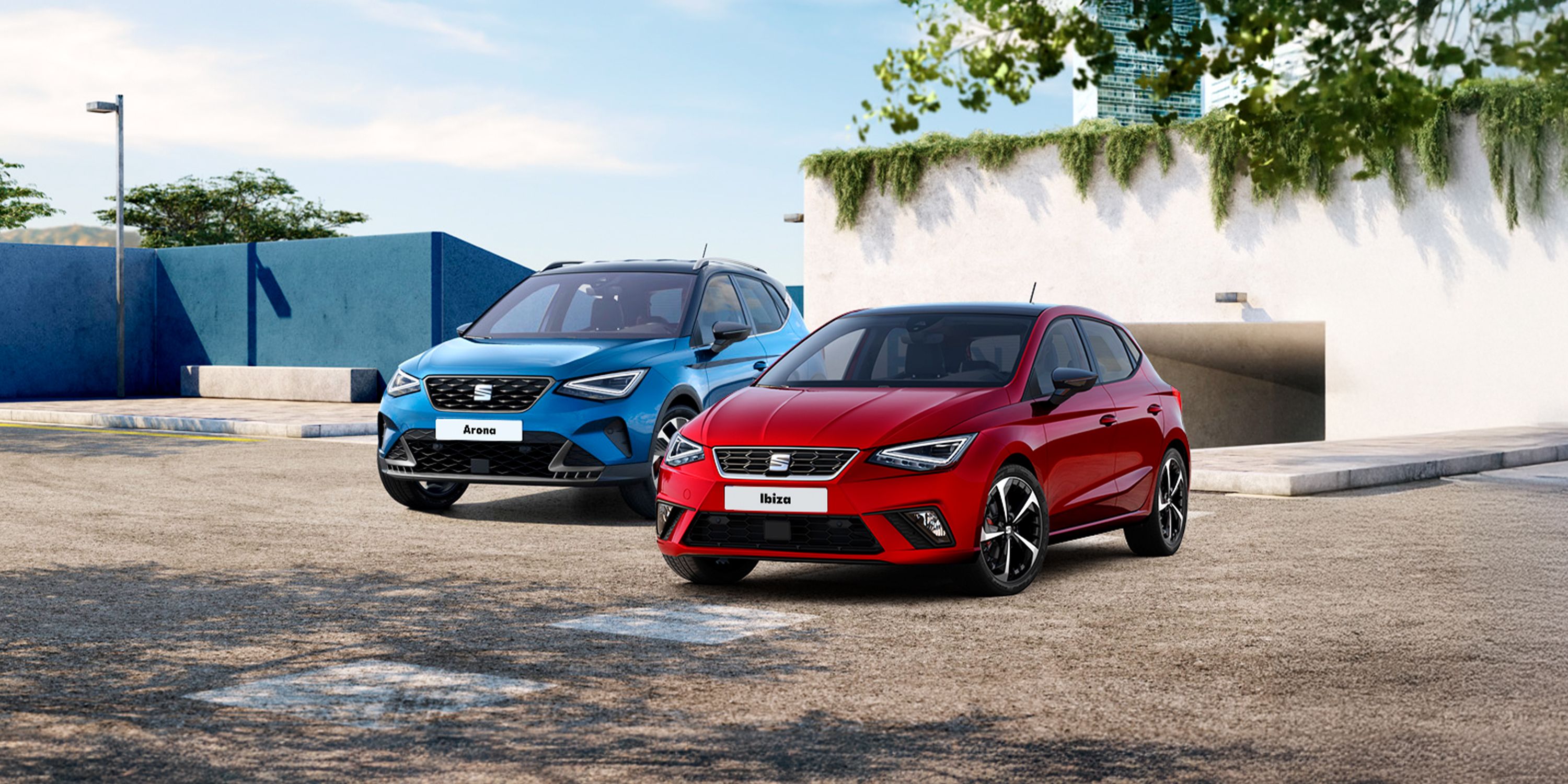 SEAT Ibiza a Arona stoja pred vchodom do moderného parkovacieho domu, ktorý je porastený zeleňou a vedľa neho vidieť časť konárov stromu.