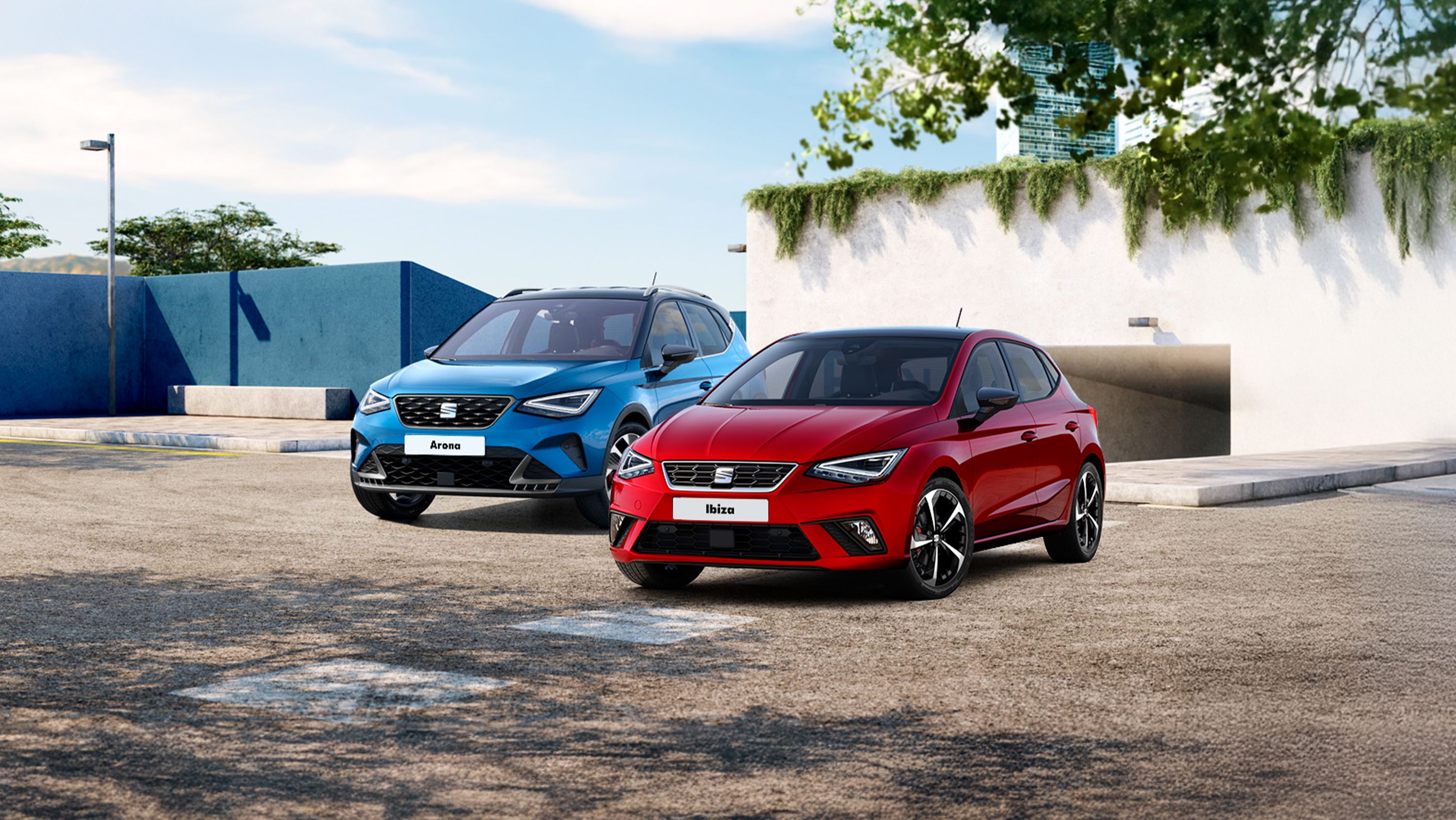 SEAT Ibiza a Arona stoja pred vchodom do moderného parkovacieho domu, ktorý je porastený zeleňou a vedľa neho vidieť časť konárov stromu.