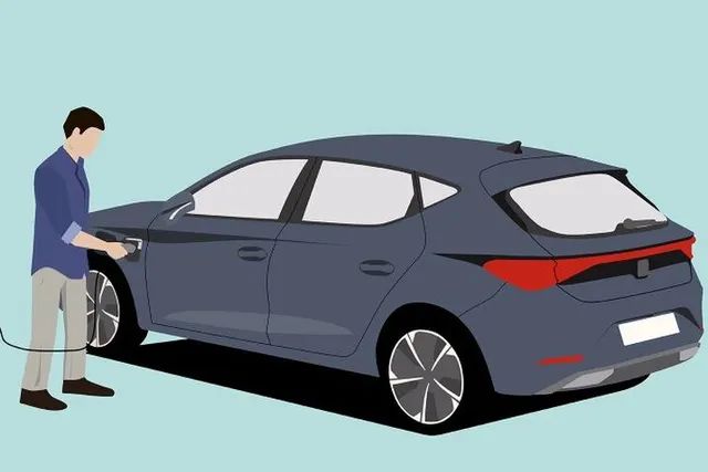 Muž zapája nabíjací konektor do automobilu.