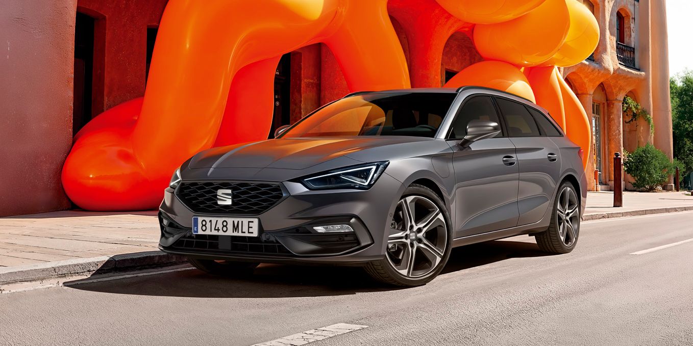 SEAT Leon stojí pred historickou budovou s modernou oranžovou inštaláciou. 
