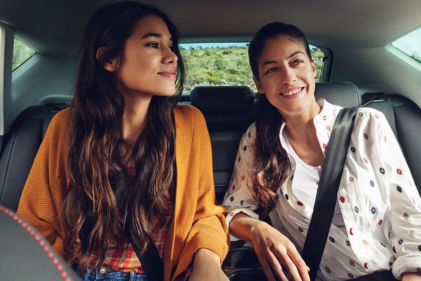 Dve ženy sedia na zadných sedadlách a cez bočné okno sa pozerajú von.