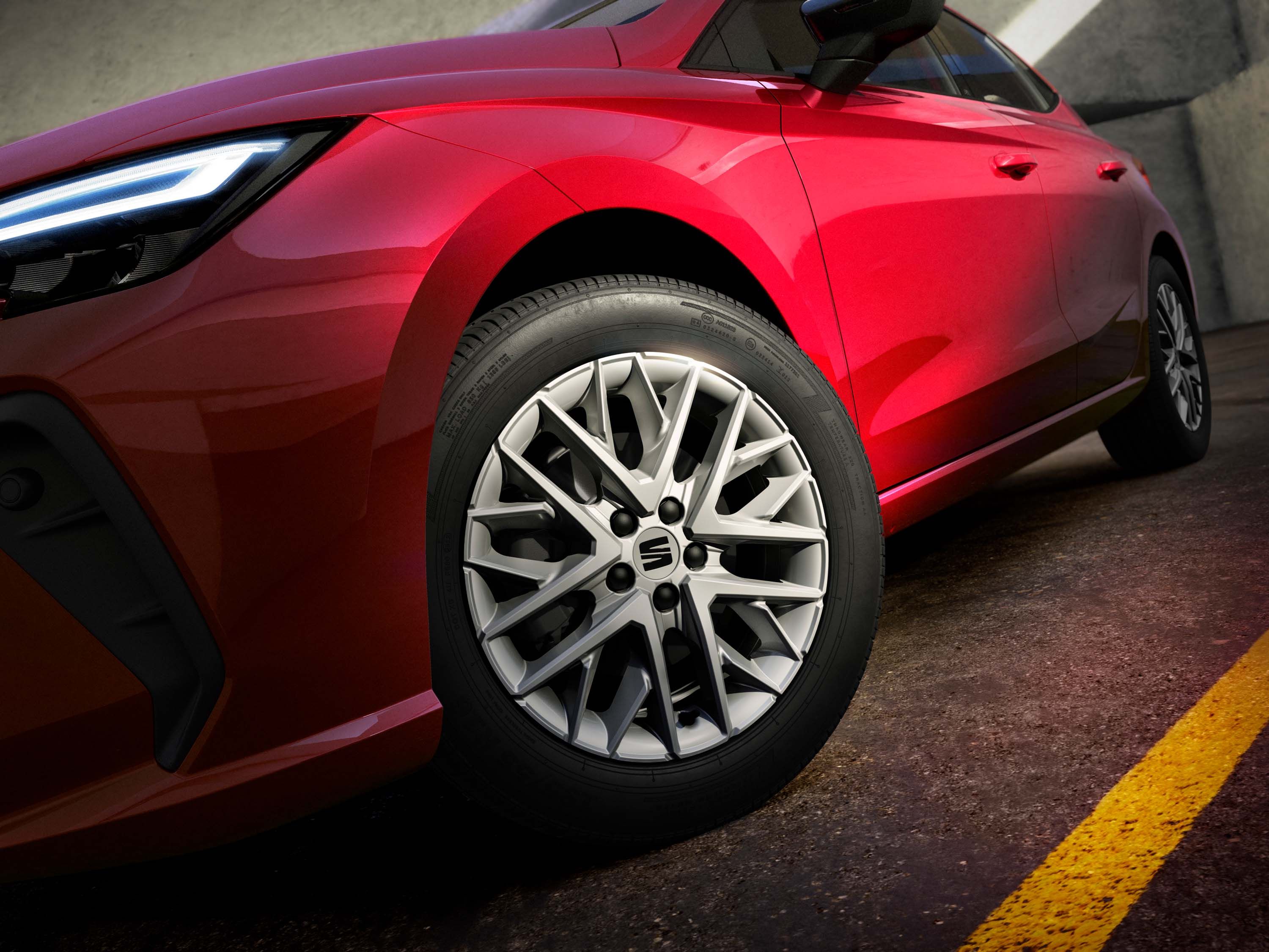 Červené športové auto zaparkované na betónovom povrchu. Lúč svetla zvýrazňuje detailné disky kolesa. Agresívny dizajn svetiel a karosérie.
