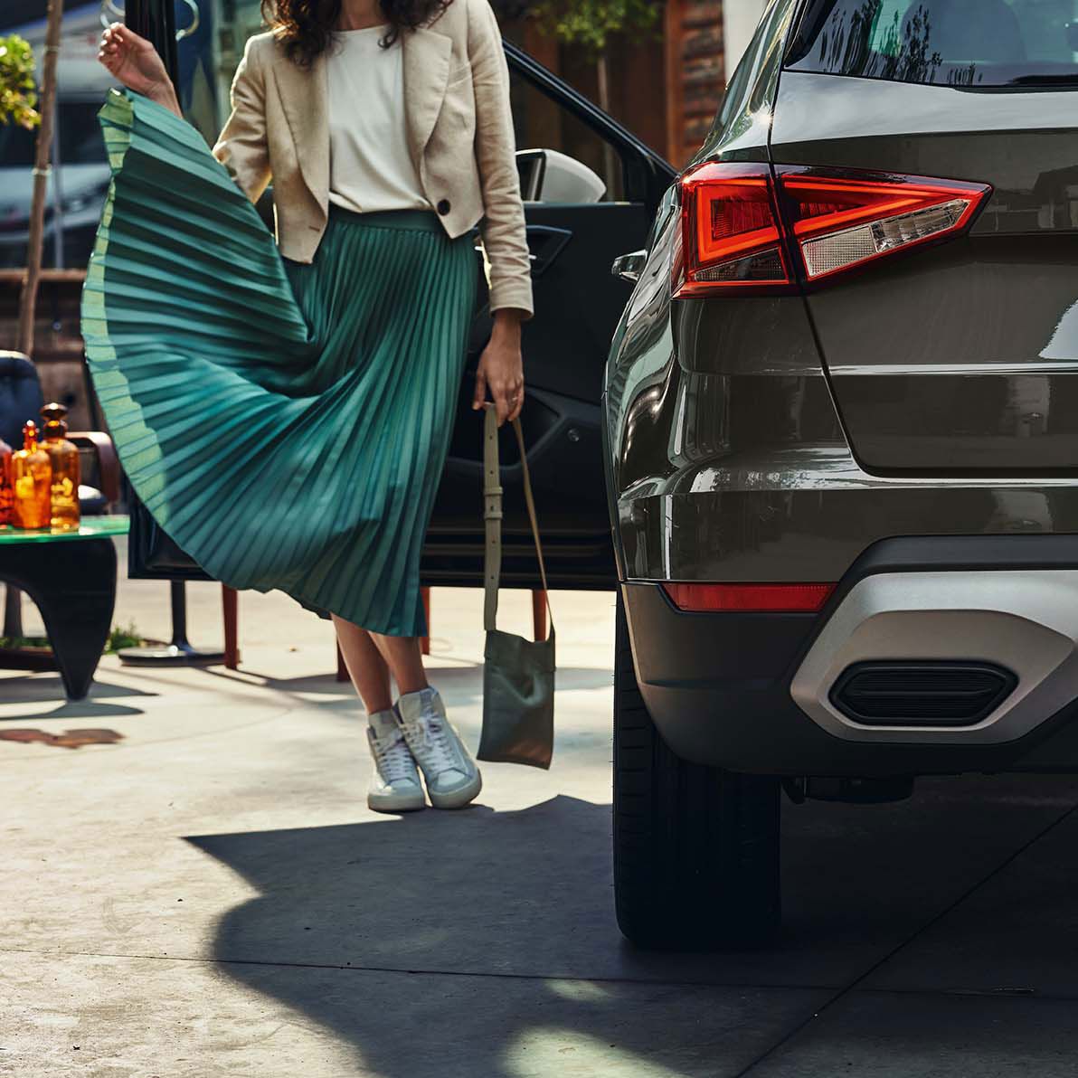 SEAT Arona je zaparkovaný v meste. Dvere vodiča sú otvorené a pri nich stojí žena.