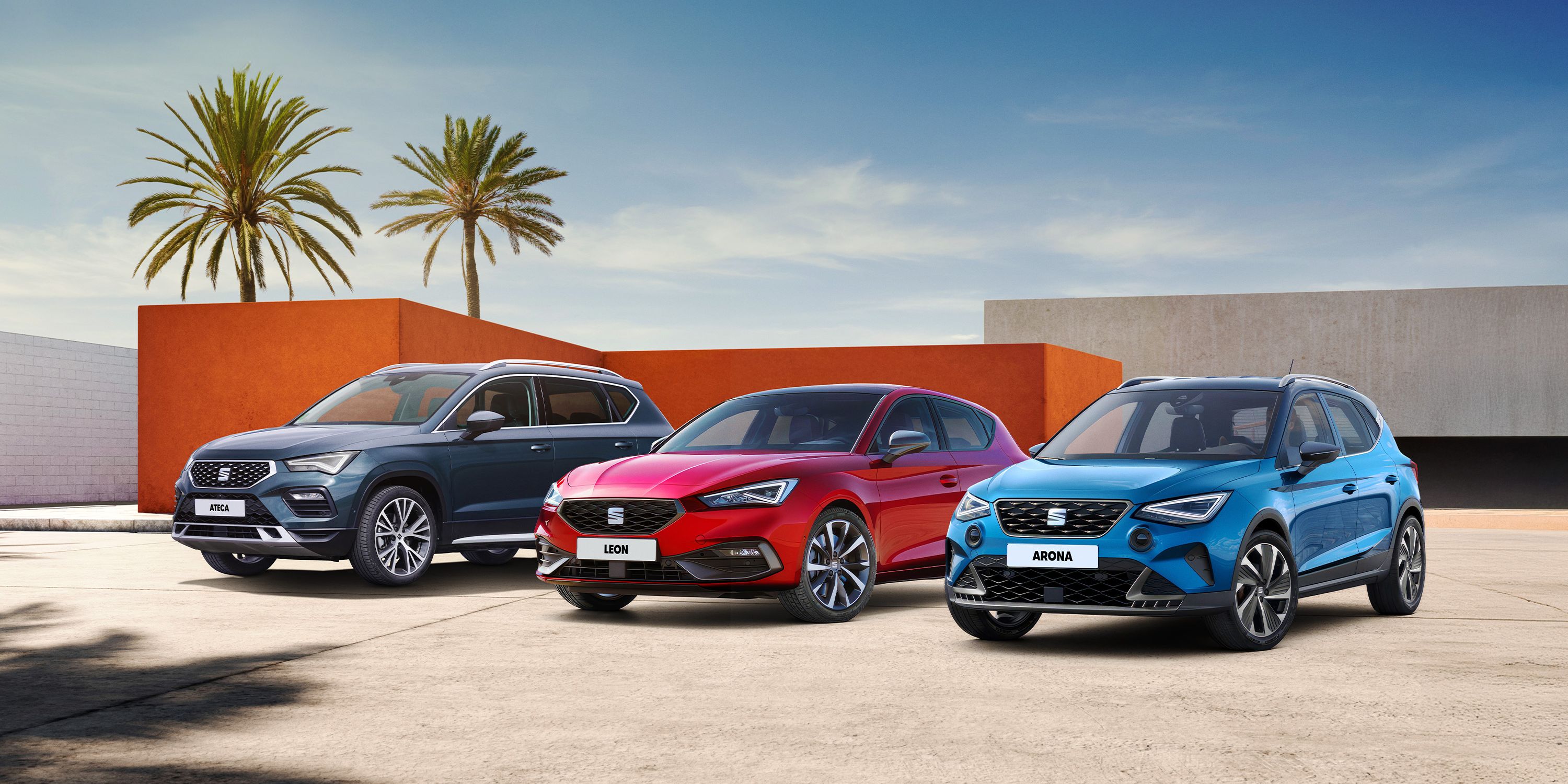SEAT Arona, Leon a Ateca stoja pred modernou stavbou domu a v pozadí stoja dve palmy.
