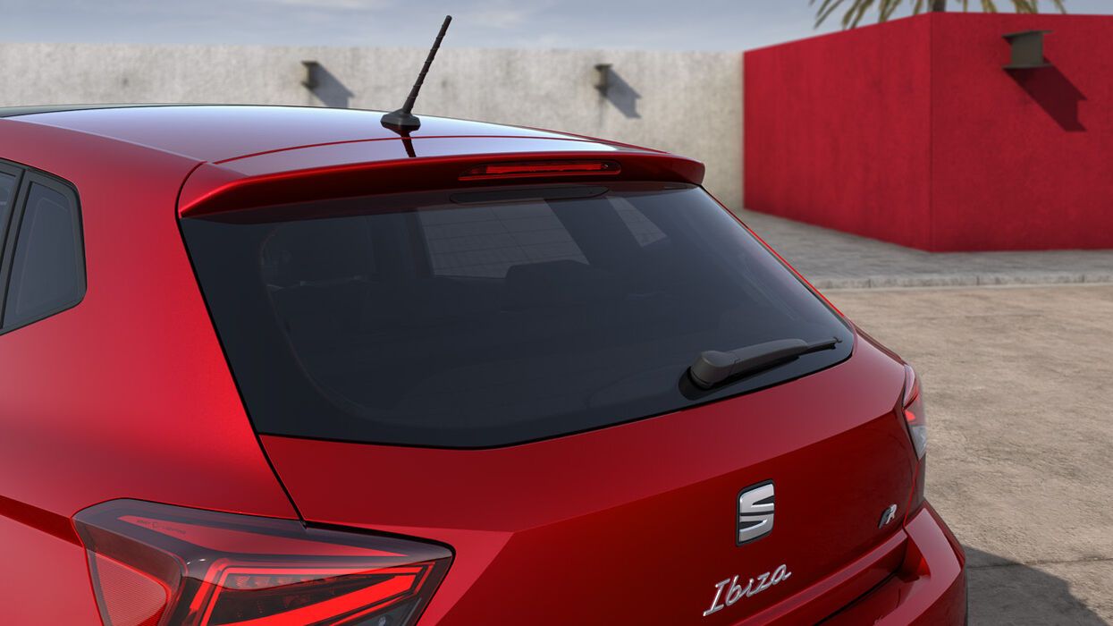 Červený SEAT Ibiza stojí pred domom. Detail na zadné partie vozidla.