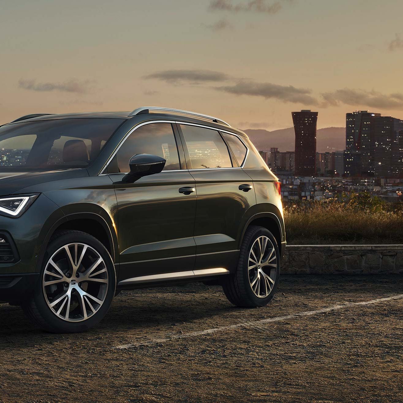 SEAT Ateca zaparkovaný na parkovisku s výhľadom na mesto za súmraku.
